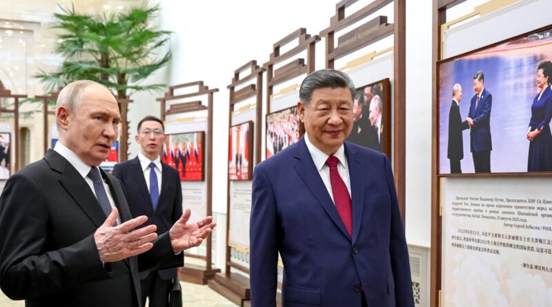 Two men in dark suits stand in a gallery lined with framed photos and large display panels of text and images in the background.
