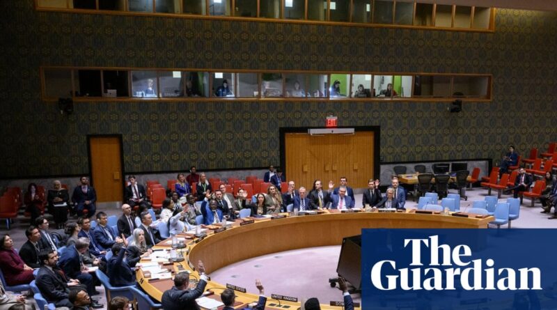 Wide view of a United Nations–style meeting room with a large circular wooden table and numerous delegates in suits seated around it, The Guardian logo overlaid in the corner.