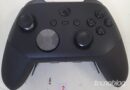 Top view of a black Xbox-like game controller with two analog sticks, D-pad, ABXY buttons, and center Xbox button; watermark TECNO BLOG visible in corner.