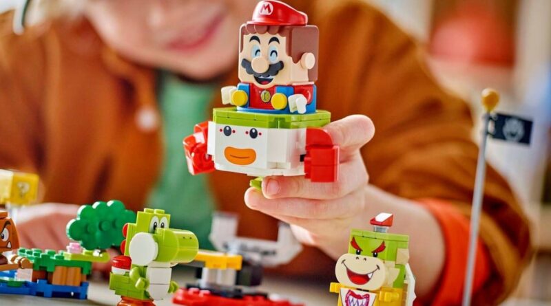 Child playing with colorful building bricks, stacking a Mario figure on a blocky animal toy.