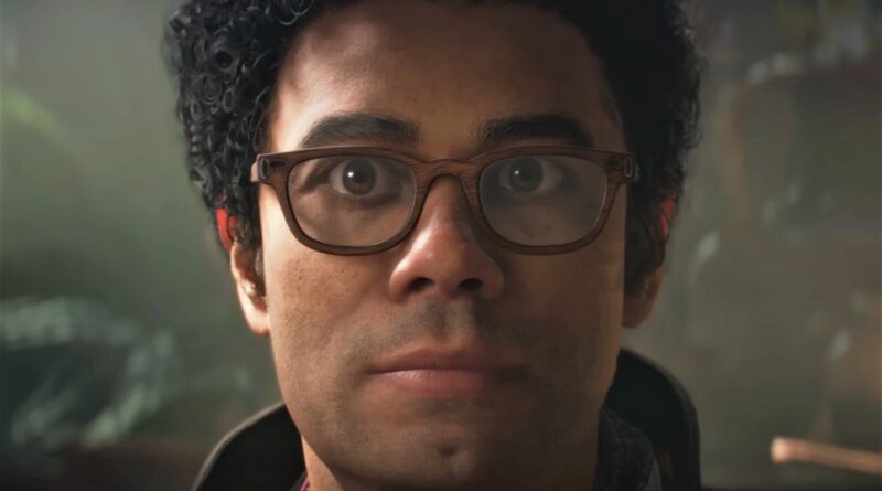 Close-up of a man with curly hair and brown-framed glasses, looking straight ahead at the camera.
