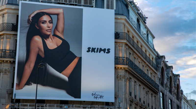 Large SKIMS billboard on a historic building featuring a woman in a black crop top and leggings.