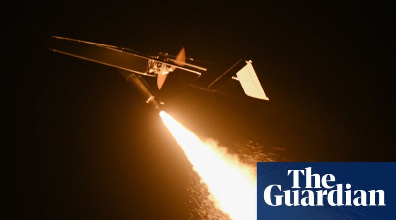 Night-time rocket launch: a small aircraft-style vehicle emits a bright flame and exhaust as it climbs, with The Guardian logo in the corner.