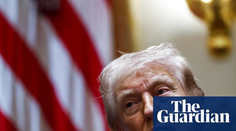 Close-up of an older man with white hair in front of waving American flags, The Guardian watermark in the corner.