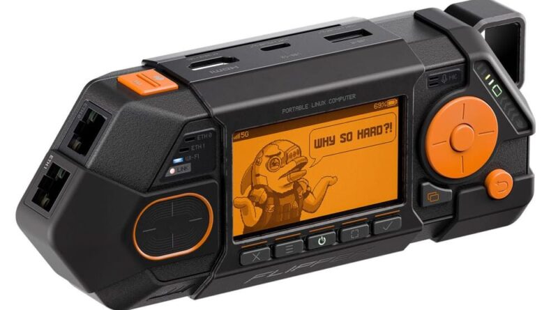 Handheld portable Linux computer with orange LCD screen displaying a cartoon character and 'WHY SO HARD?!', orange control knob on the right, and ports on top.