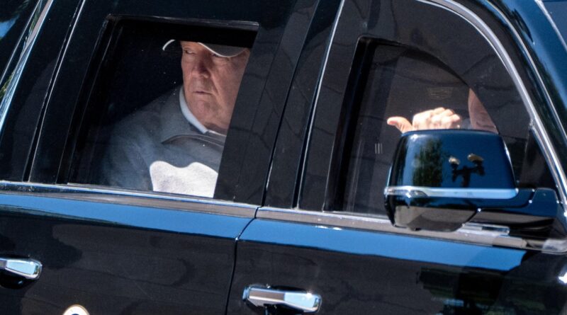 Close-up of a dark luxury SUV showing two men inside the back seat, one wearing a cap and looking down, with chrome trim along the door.