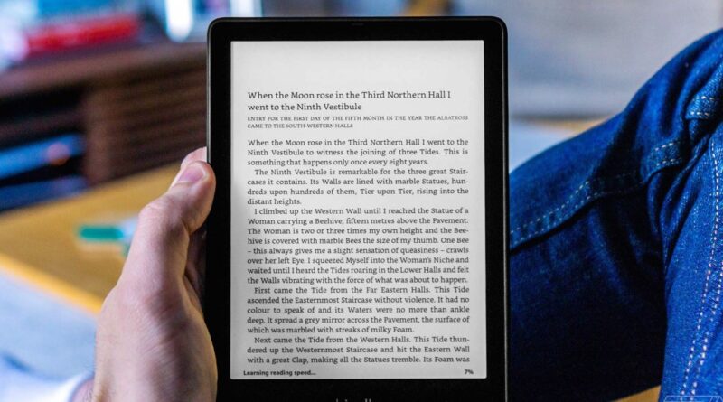 Close-up of a hand holding a tablet that displays a full page of dense book text.