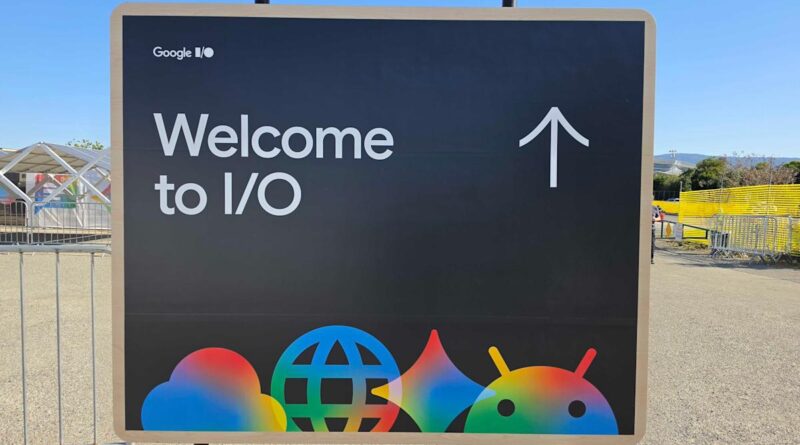 Sign reading 'Welcome to I/O' with an upward arrow, welcoming visitors to Google I/O; colorful Google/Android logos at the bottom.
