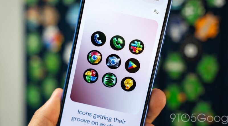 Hand holding a phone showing nine colorful circular app icons on a pink card, with a blurred background.