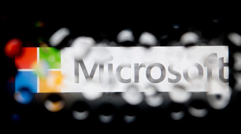 Microsoft logo with color blocks on the left and blurred white confetti in the foreground, dark background.