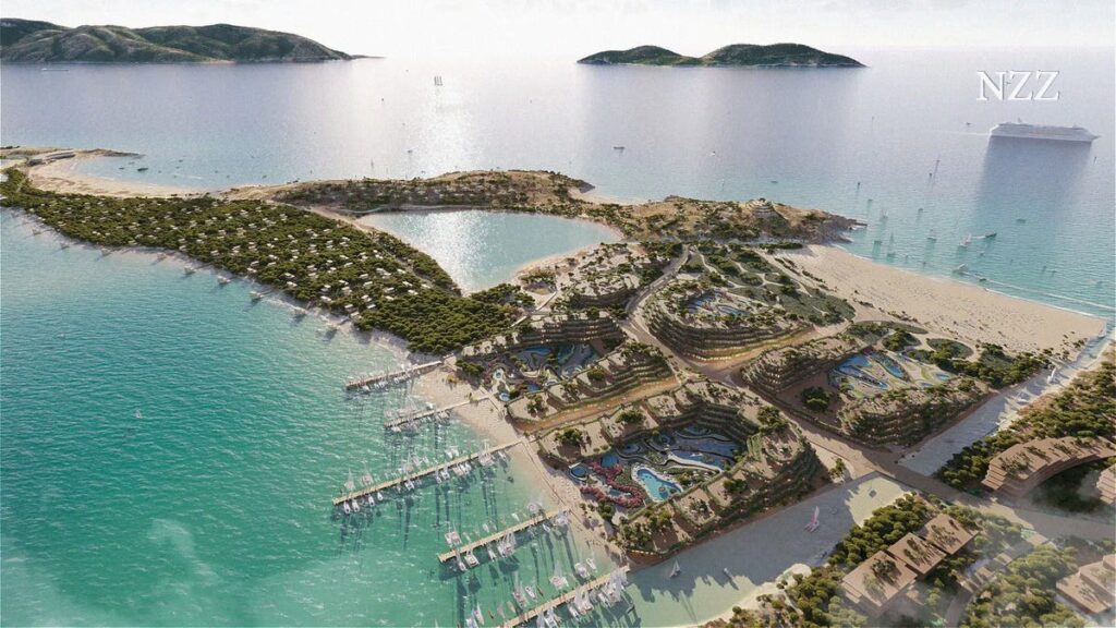 Aerial view of a coastal resort on a sandy peninsula with terraced gardens, pools, and a marina along turquoise water.”