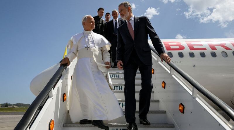 Religious leader in white robes descends stairs from a jet with a suited companion on a sunny tarmac.