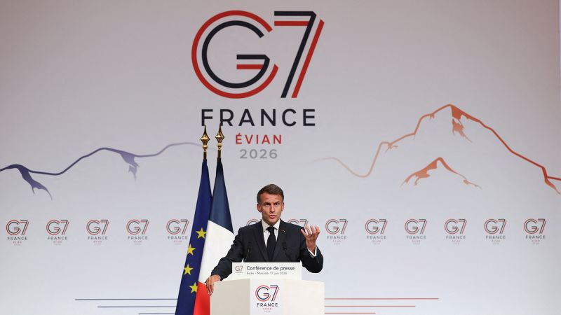 Man in a suit giving a press conference at the G7 France Evian 2026 stage, with EU and French flags behind him.