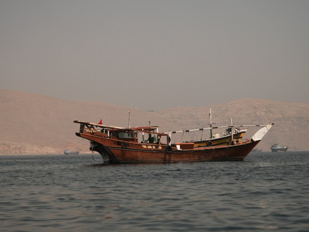 Traditional wooden boat anchored on calm water with arid hills in the background