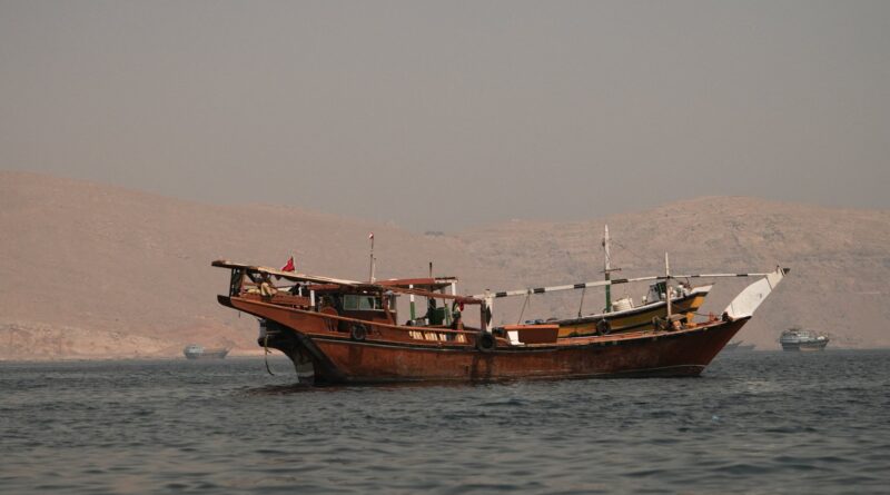 Traditional wooden boat anchored on calm water with arid hills in the background