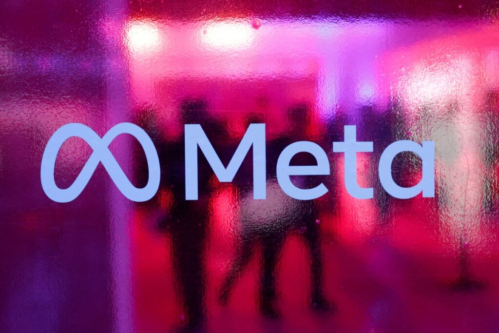 Meta logo on a glass surface with pink and purple neon reflections behind it.