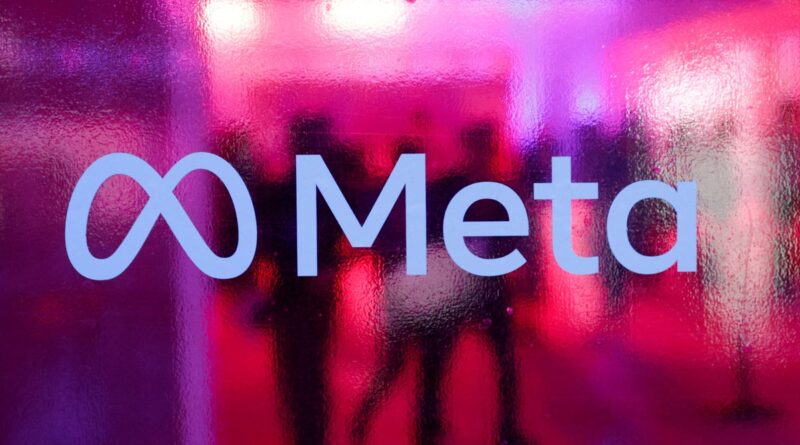 Meta logo on a glass surface with pink and purple neon reflections behind it.