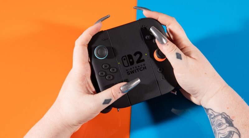 Close-up of hands holding a Nintendo Switch game console against an orange and blue background.