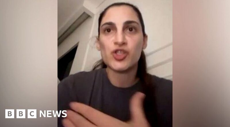 BBC News clip: woman speaks directly to the camera in a gray shirt, indoors, mid-speech (BBC News watermark lower left).
