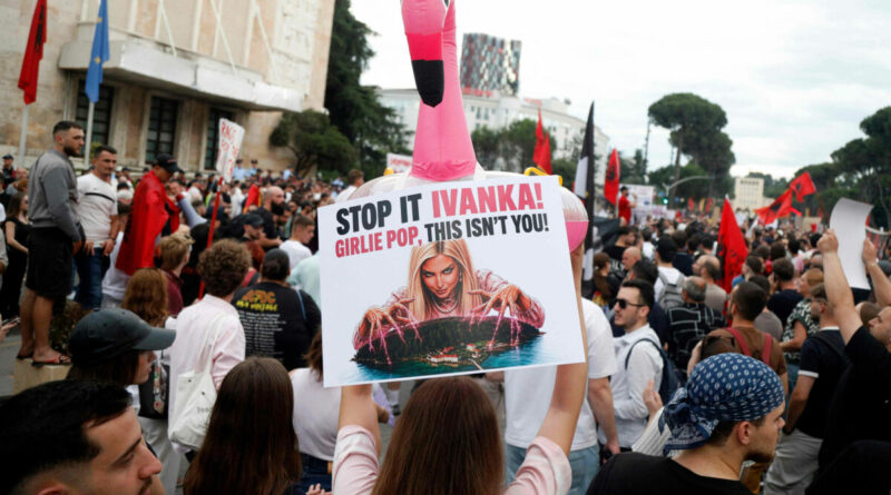 Protest crowd with a sign reading 'STOP IT IVANKA! GIRLIE POP, THIS ISN'T YOU!' and a tall pink flamingo balloon above the crowd.