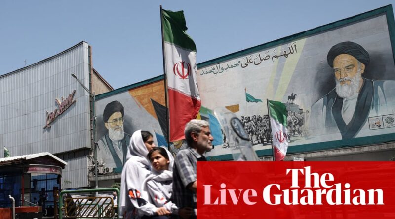 Iranian street scene with a large mural of a cleric on a wall, an Iranian flag, and pedestrians in the foreground.