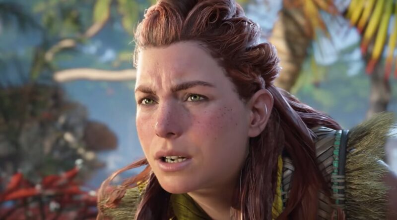 Close-up of Aloy, a red-haired, freckled video game character, looking surprised in a tropical jungle setting with palm leaves in the background.