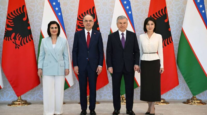 Four officials stand in a row in front of alternating Albanian and Uzbek flags during a formal diplomatic photo.** This seems to have a stray asterisks; remove in final.
