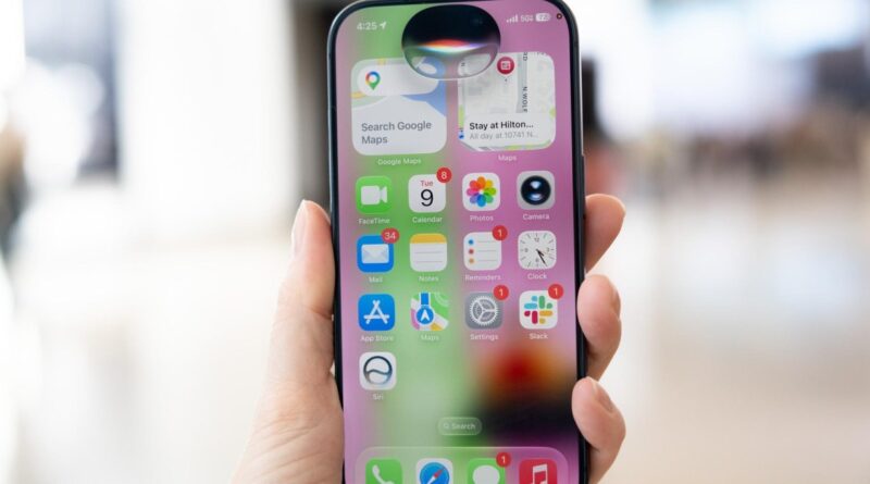 Close-up of a hand holding an iPhone displaying colorful app icons on the home screen
