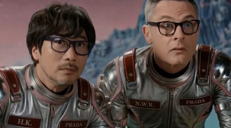 Two men in metallic spacesuits with Prada patches and initials, wearing glasses, look surprised in a pink‑sky, icy landscape.