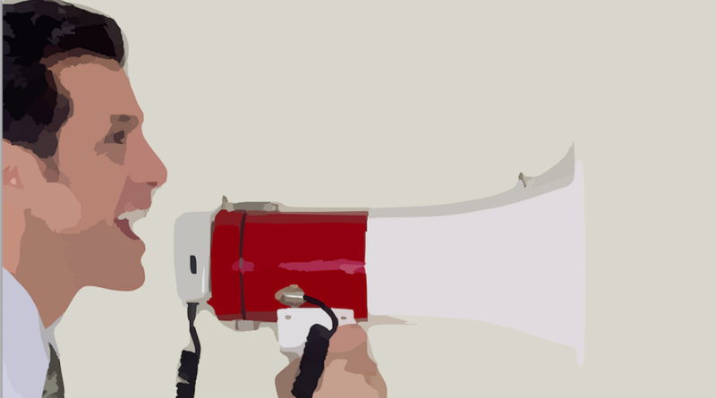 Man in profile speaking into a red megaphone to amplify his voice.