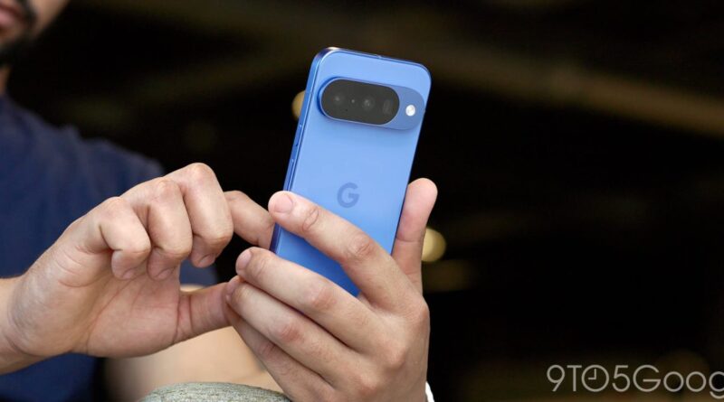Person holding a blue Google Pixel smartphone, showing the large horizontal camera bar on the back.