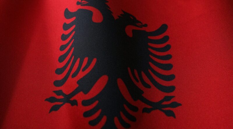 Close-up of a red fabric flag featuring a black double-headed eagle (Albania flag) texture visible in the weave