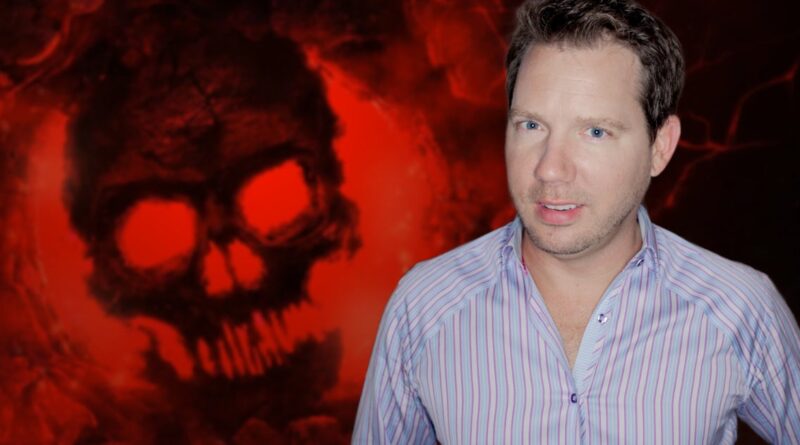 Portrait of a man in a light striped shirt posing in front of a red skull backdrop