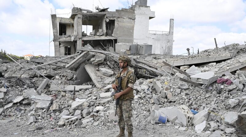 Soldier in camouflage and helmet stands amid rubble of a destroyed building with scattered concrete and debris.