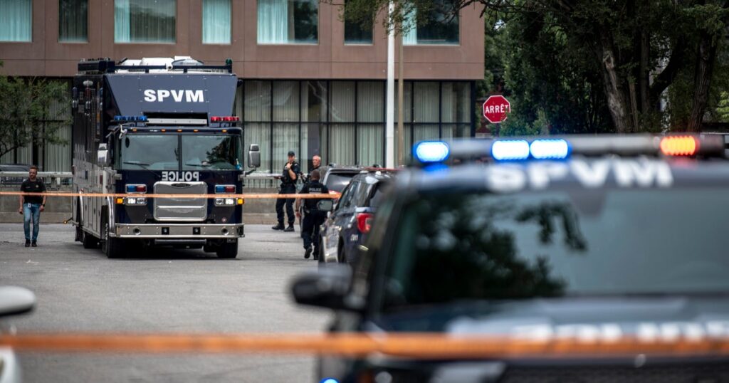 Armored SPVM police vehicle blocking a street with officers and orange tape at a scene gone under investigation in front of a building.