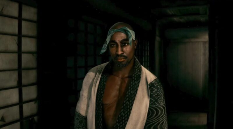 A man wearing a patterned robe with a blue headscarf stands in a dimly lit hallway, looking toward the camera.