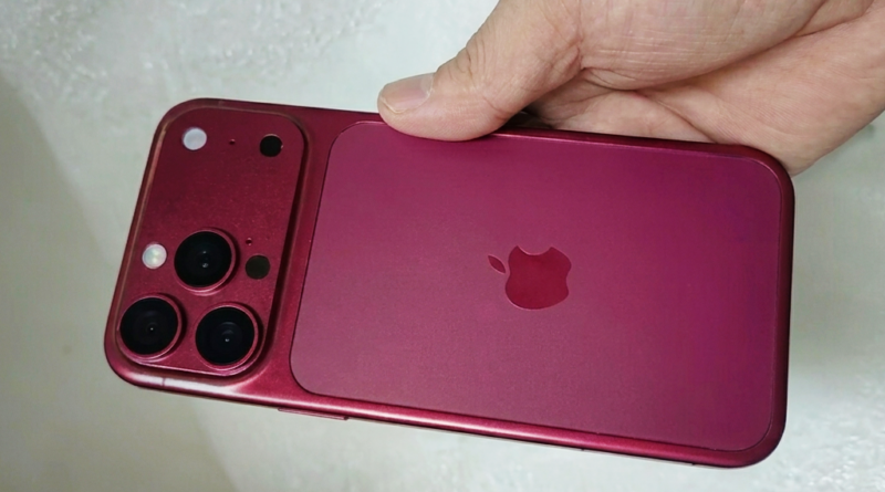Pink iPhone back with triple-camera array held in a hand, Apple logo visible
