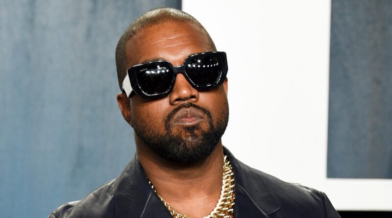 Close-up of a man with a shaved head wearing oversized black sunglasses and a gold chain.