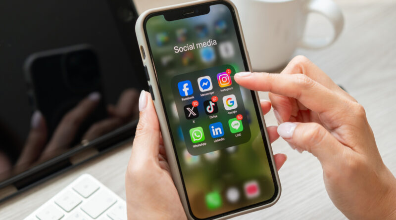 Close-up of a smartphone screen showing a 'Social media' folder and app icons; a finger taps Instagram.
