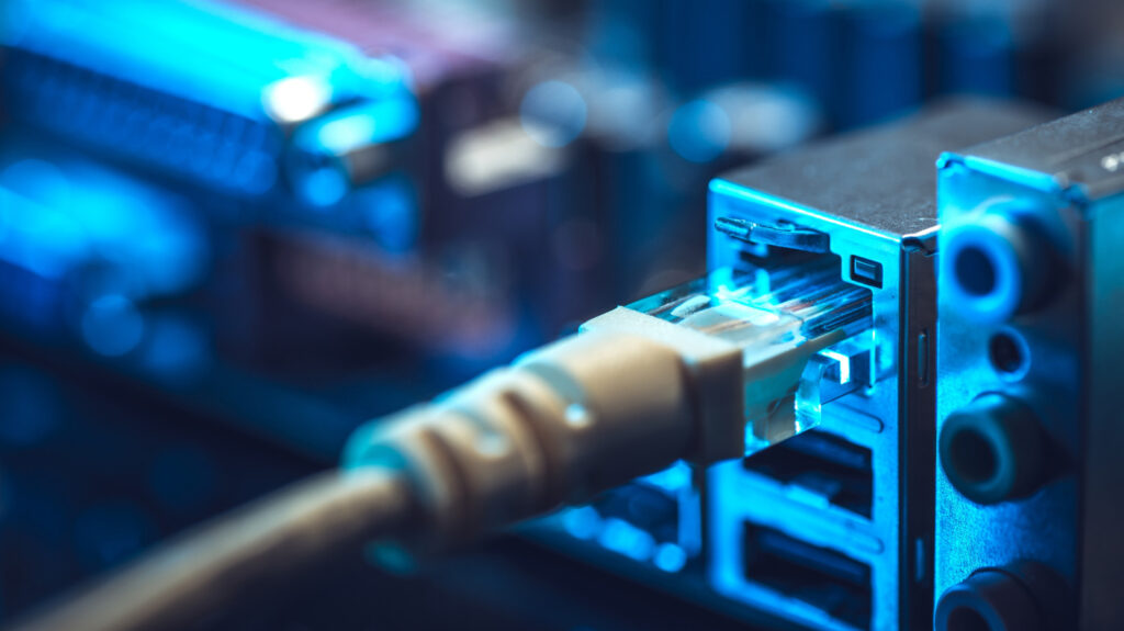 Ethernet cable plugged into a metal network device with blue LED lighting