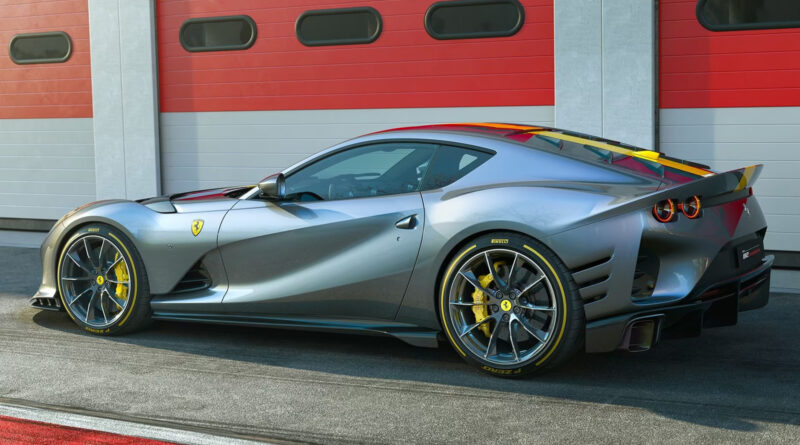 Side view of a metallic gray Ferrari sports car with yellow brake calipers parked in front of a red garage building.