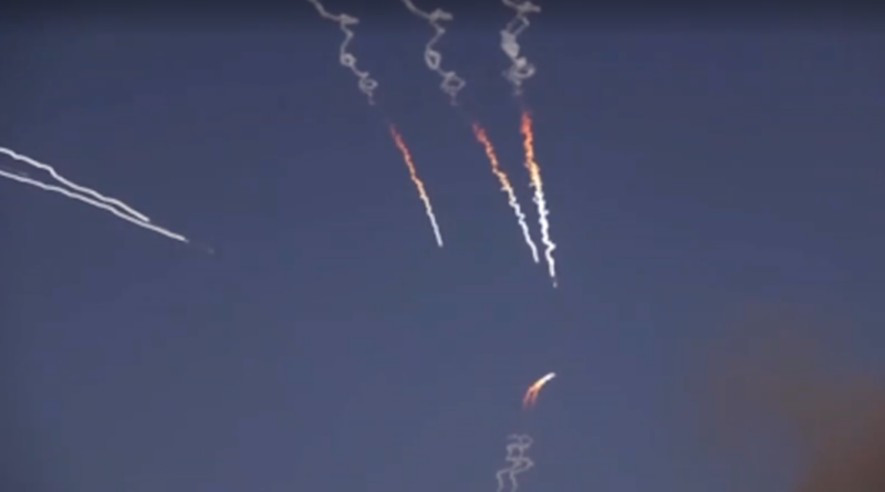 Several colorful rocket trails burning in a dark sky with spiraling smoke patterns.
