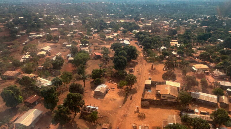 Aerial view of a dusty rural town with scattered houses, dirt roads, and trees