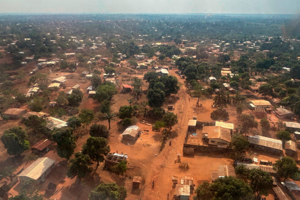 Aerial view of a dusty rural town with scattered houses, dirt roads, and trees