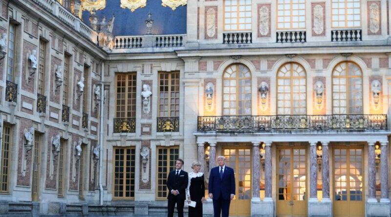 Three formally dressed adults stand on a checkered courtyard in front of an ornate historic palace façade with gold accents.