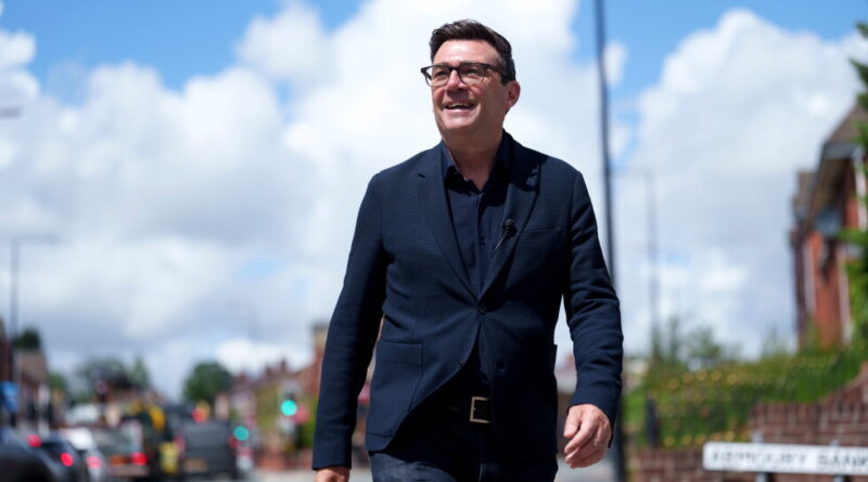 Man in a dark suit and glasses walking on a sunny city street, smiling. Unsure? (Informative)