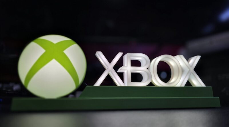 Xbox branding display: illuminated white XBOX letters beside a large lime-green sphere on a dark background, mounted on a green pedestal.